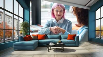 Recruitment concept. Handshake happy young woman with a recruiter after a successful job interview for her first job Wall mural