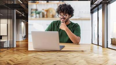 Smiling Asian man student or freelancer using laptop computer to watch online webinar or training, education, studying, distance learning at home Wall mural