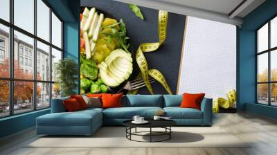 Vegan healthy balanced diet. Vegetarian buddha bowl with blank notebook and measuring tape. Сhickpeas, broccoli, pepper, tomato, spinach, arugula and avocado in plate on dark background. Top view Wall mural