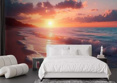 A vibrant sunset paints the sky in hues of orange, pink, and purple as the sun dips below the horizon over the calm, clear ocean waves. Wall mural