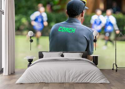 Male soccer or football coach standing on the sideline watching his team play Wall mural