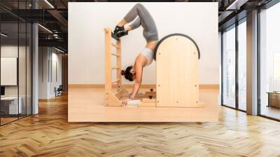 Young Asian woman working on pilates ladder barrel machine during her health exercise Wall mural