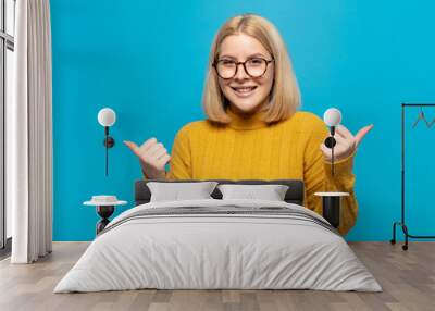 blonde woman smiling joyfully and looking happy, feeling carefree and positive with both thumbs up Wall mural