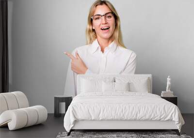 caucasian blonde woman looking excited and surprised pointing to the side Wall mural