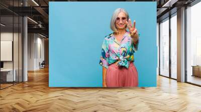 middle age cool woman smiling and looking friendly, showing number three or third with hand forward, counting down Wall mural