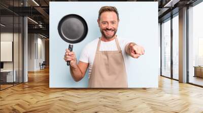 middle age handsome man pointing at camera choosing you. frying pan concept Wall mural