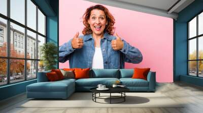 middle age hispanic woman smiling broadly looking happy, positive, confident and successful, with both thumbs up Wall mural