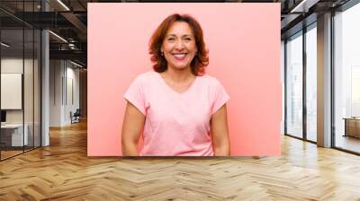 middle age woman looking happy and goofy with a broad, fun, loony smile and eyes wide open against pink wall Wall mural