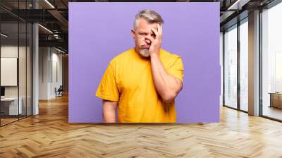 old senior man feeling bored, frustrated and sleepy after a tiresome, dull and tedious task, holding face with hand Wall mural