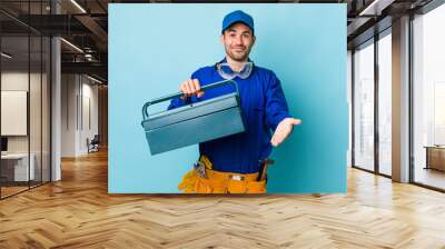 young adult hispanic man smiling happily with friendly and  offering and showing a concept. toolbox concept and plumber Wall mural