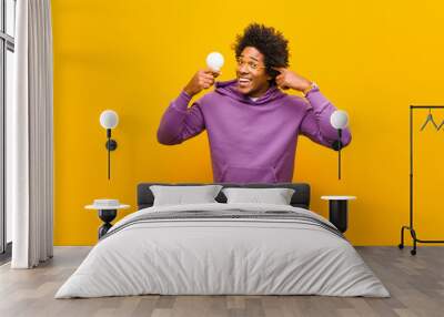 young african american man with a light bulb against orange back Wall mural