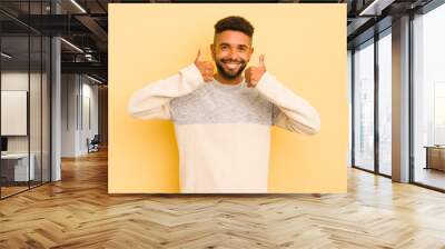 young afro man smiling broadly looking happy, positive, confident and successful, with both thumbs up Wall mural