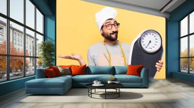 young bearded chef man doubting or uncertain expression and holding a scale Wall mural