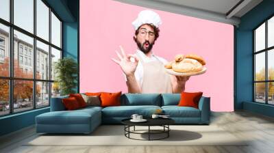 young crazy baker man holding bread against pink wall Wall mural