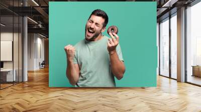 young handsome blond man with a chocolate donut. breakfast concept Wall mural