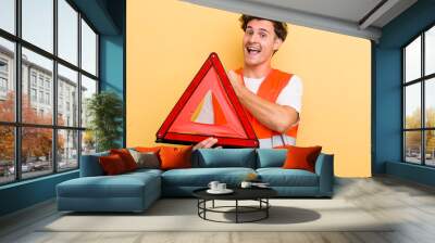 young handsome guy feeling happy and facing a challenge or celebrating. car emergency triangle concept Wall mural