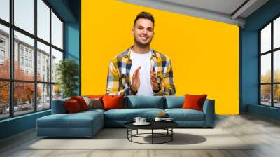 young hispanic man feeling happy and successful, smiling and clapping hands, saying congratulations with an applause against orange wall Wall mural