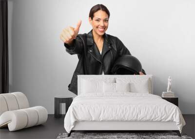 young hispanic woman feeling proud,smiling positively with thumbs up. motorbike rider concept Wall mural