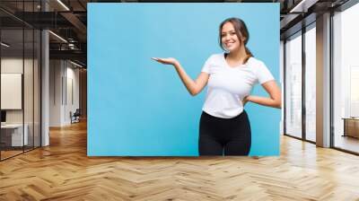 young hispanic woman smiling, feeling confident, successful and happy, showing concept or idea on copy space on the side Wall mural