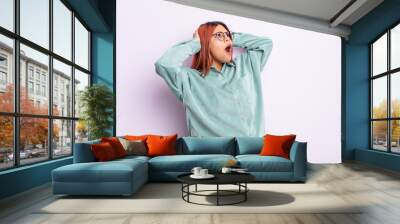 young hispanic woman with open mouth, looking horrified and shocked because of a terrible mistake, raising hands to head Wall mural