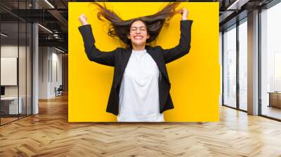 young  pretty woman looking extremely happy and surprised, celebrating success, shouting and jumping against orange wall Wall mural