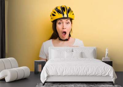 young pretty woman looking shocked and surprised with mouth wide open, pointing to self. bike helmet concept Wall mural