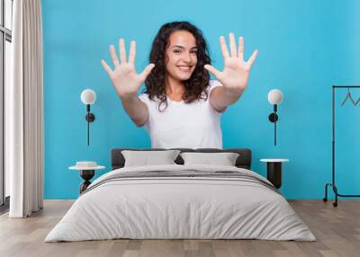 young pretty woman smiling and looking friendly, showing number ten or tenth with hand forward, counting down against blue background Wall mural