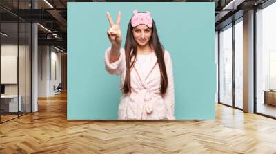 young pretty woman smiling and looking friendly, showing number two or second with hand forward, counting down. awaking wearing pajamas concept Wall mural