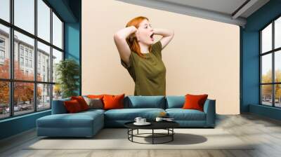 young red head pretty woman with open mouth, looking horrified and shocked because of a terrible mistake, raising hands to head Wall mural