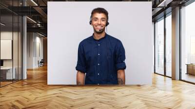 young telemarketer man smiling happily with a hand on hip and confident, positive, proud and friendly attitude Wall mural