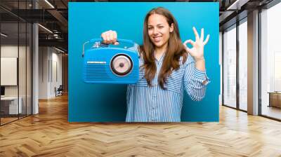 young woman with a vintage radio against blue background Wall mural