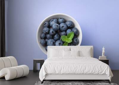 fresh juicy blueberries with mint in a white bowl on a blue background Wall mural