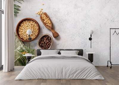 Pine nuts in a bowl and wooden scoop  on a napkin on a light texture background with branches of pine needles. The concept of a natural, organic and healthy superfood and snack. Wall mural