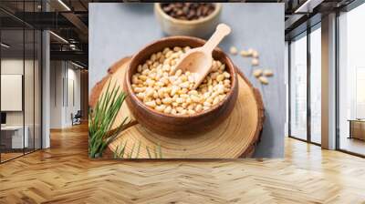 Pine nuts in a bowl on a wooden board on a blue texture background with branches of pine needles and a cone close up. The concept of a natural, organic and healthy superfood Wall mural