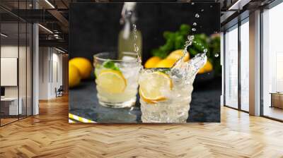 Two glasses of Lemonade drink with fresh lemon and splashes. Refreshing cocktails with lemons, mint and ice on dark background. Summer cold drinks concept Wall mural