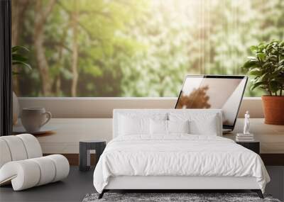 Work wooden desk with laptop, coffee cup and houseplant  in front of window with landcape and morning sunlight. Wall mural