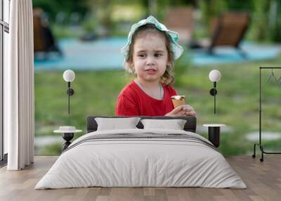 Little girl eating ice cream in the park in summer. Close-up portrait of a child Wall mural