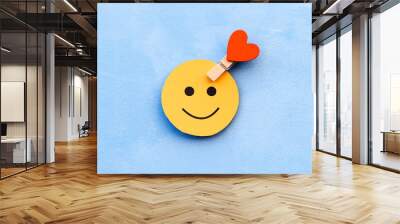 yellow happy smiley face on a blue background and a red heart as the emotion selection. The concept of mood selection and customer feedback. Copy space, business and emotions. Wall mural