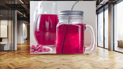 Glass cup and jug with raspberry drink on a light wooden table and with a saucer of raspberries Wall mural