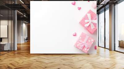 Two pink gift boxes with white ribbons and hearts, surrounded by small heart decorations, create festive and romantic atmosphere perfect for celebrations Wall mural