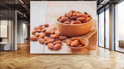 Almonds in a wooden bowl The nuts are freely placed on the dark board. Wall mural