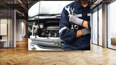 Hand of car mechanic with wrench. Auto repair garage. mechanic works on the engine of the car in the garage. Repair service. Concept of car inspection service and car repair service. Wall mural