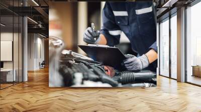 Mechanic works on the engine of the car in the garage. Repair service. Concept of car inspection service and car repair service. Wall mural