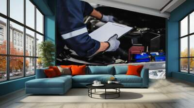 professional mechanic working on the engine of the car in the garage. car repair service. Wall mural