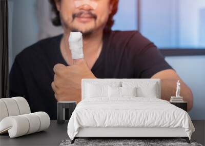 Shot image of Asian man show his fingers in a bandage, finger injury in a man, thumb gauze bandage. Wall mural