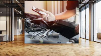 Shot of professional technician car mechanic man's hand hold a mobile cell phone browsing fix problem. Wall mural