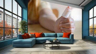 White medicine bandage on older woman injury hand finger. Selective focus. Wall mural