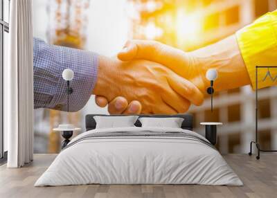 close up photo of two hands shaking, symbolizing partnership and collaboration in construction setting. warm light adds positive and optimistic atmosphere to image Wall mural