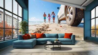 A family running on the beach with their SUV parked nearby, with closeup focus of wheels and sand in the foreground, a blurred depth background showing the ocean and sky, on a sunny day... Wall mural