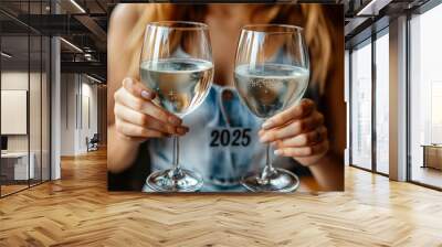 Close-up of a woman holding two glasses with white wine, clinking and toasting at a New Year's Eve party, with 